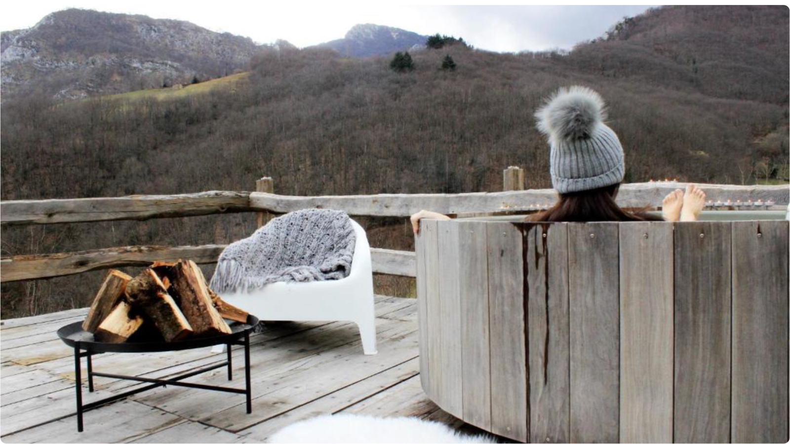 Terraza en invierno con bañera de leña y montañas nevadas